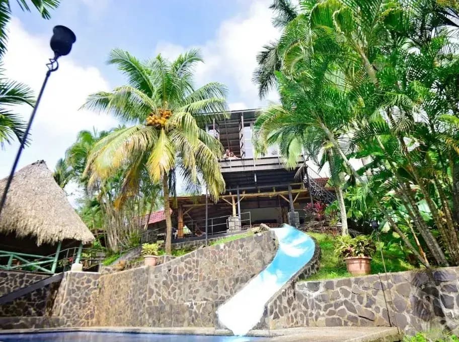 Jungleland tropical paradise with blue waterslide pool, palapa, and lush palm trees in Playa Hermosa