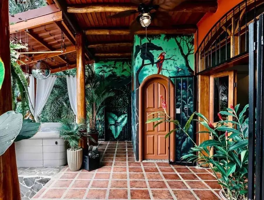 Villa Mariposa jungle-inspired tropical beach house entrance with macaw wall mural and hot tub