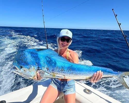 Young woman triumphantly holding large mahi-mahi caught on offshore fishing charter in Costa Rica